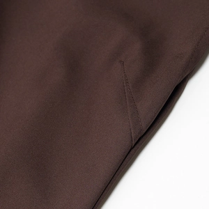 Detailed close-up of side slit stitching on a dark brown pleated sleeveless dress