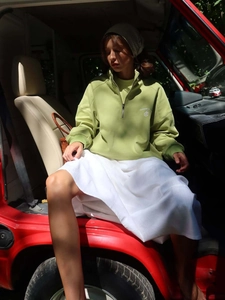 Sudadera verde aguacate con cremallera media y bordado blanco en un coche clásico exterior