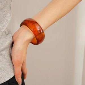 Close-up of amber resin bangle with marbled texture worn on a model's wrist