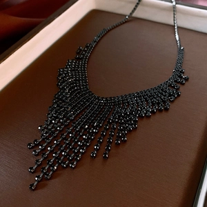 Close-up of black rhinestone tassel necklace with V-shaped fringe in a jewelry box