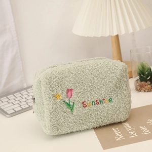 Detail of green plush makeup bag with pink tulip embroidery and Sunshine text