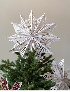Detailed view of white paper star tree topper with red candy cane hollow patterns