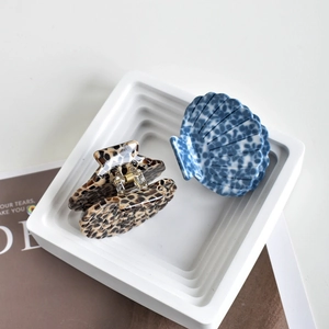 Minimalist shell-shaped acetate hair claws in tortoise shell and blue marble patterns