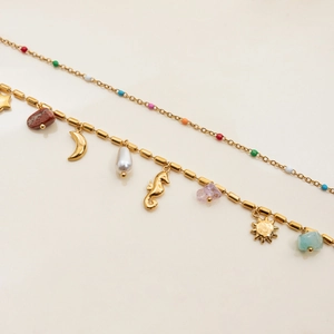 Macro detail of gold-plated chain featuring colorful stones, moon, and pearl charms