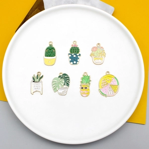 Detailed macro view of colorful enamel plant charms including cactus and monstera leaf