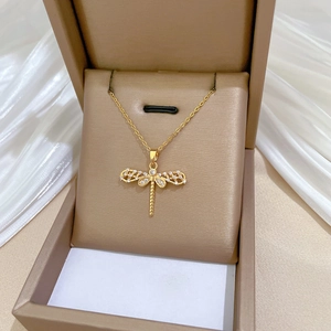 Detailed macro view of a gold dragonfly pendant necklace in a luxury jewelry box