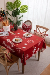 Close-up of red Christmas tablecloth with white snowflake patterns and festive lettering