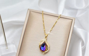Macro detail of gold teardrop pendant with purple gradient crystal and clear accents