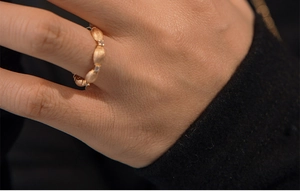Macro shot of rose gold leaf ring with fine zircon stones on model's finger