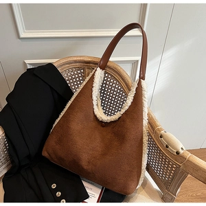 Detail of a brown suede tote bag with white faux fur trim on a vintage wooden chair