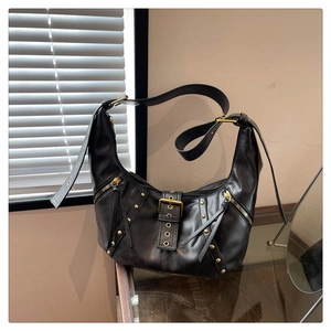 Detail of vintage black hobo bag with gold metal rivets and decorative zippers