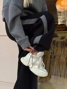 Dettaglio della coulisse regolabile sui pantaloni sportivi grigi e neri a contrasto