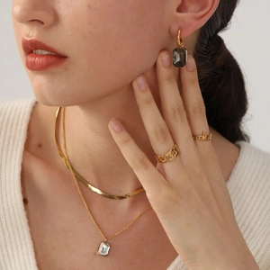 Dettaglio collana a serpente dorata con orecchini di zircone su maglione bianco
