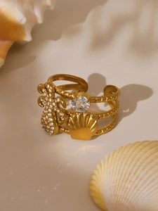 Detail of gold pineapple and shell charms on a spiral multi-layer open bangle bracelet