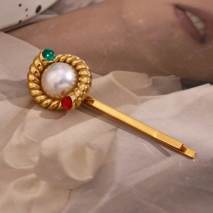 Detail of gold twisted hair clip with center pearl and red-green side gemstones
