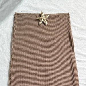 Detailed view of the starfish metal accessory on a brown knitted bikini skirt