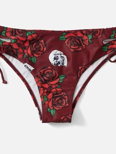 Détail du bas de bikini rouge avec imprimé rose et tête de mort et cordons sur les côtés