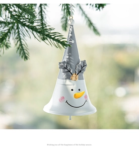 Close-up of white snowman iron bell with carrot nose hanging on a Christmas tree branch