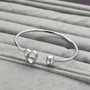 Detail of silver heart bangle with Love engraving and white rhinestone on a jewelry tray