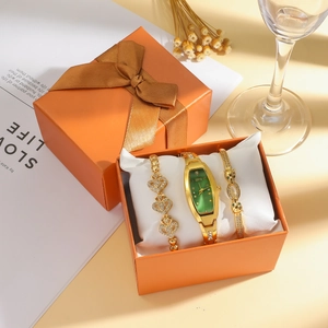 Gros plan sur l'élégante montre à cadran vert et coffret de bijoux dorés dans une boîte orange