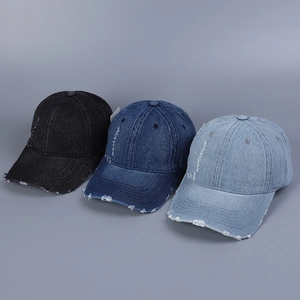 Close-up detail of distressed denim baseball caps in black and blue with frayed holes