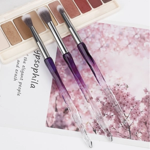 Detail of three crystal eye brushes with purple gradient faceted handles and dual-tone bristles