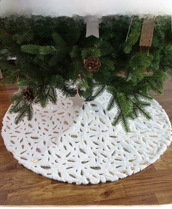 Detailed view of white plush Christmas tree skirt with elegant gold foil feather patterns