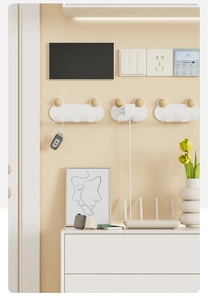 Close-up of minimalist wall-mounted cable organizer hooks for power plugs and keys