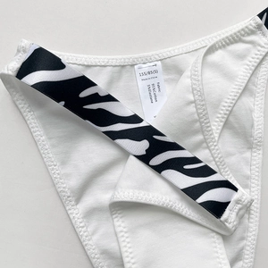 Close-up of white cotton V-neck panties with zebra print elastic waistband and size label