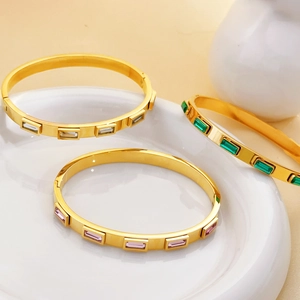 Detail view of 18K gold plated bangles with colorful rectangular zircon stones in a tray