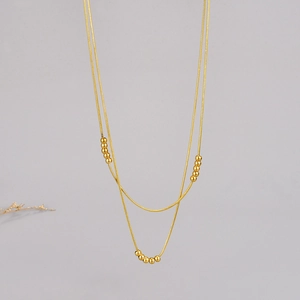 Detailed view of layered 18K gold snake chains with minimalist polished metal beads