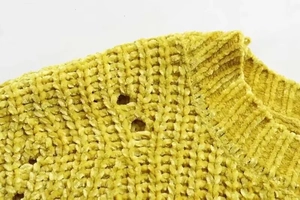 Detail of yellow chenille knit sweater showing round neck and hollow knit texture