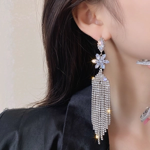 Close-up of elegant silver tassel flower earrings worn by a model in black attire