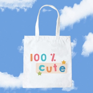 White canvas tote bag with 100% cute print and star design against a blue sky background
