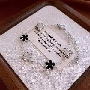Elegant gold-plated geometric clover bracelet with silver, black, and white charms