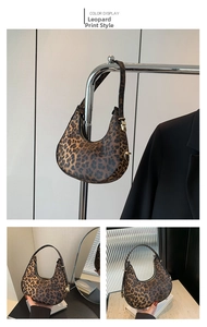 Dettagli di una borsa a mezzaluna leopardata con cerniera dorata e manico fisso