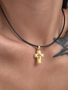 Detail of 18k gold plated vintage cross pendant with embossed pattern on black cord