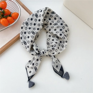 Detailed view of polka dot cotton linen scarf with black tassels on white surface