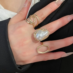 Detailed view of three gold rings featuring baroque pearl and twisted knot textures