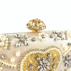 Detailed close-up of handmade pearl embroidery and floral rhinestone clasp on dinner bag