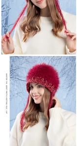 Detail of dark red knit winter hat with colorful beads and tassels in snow forest