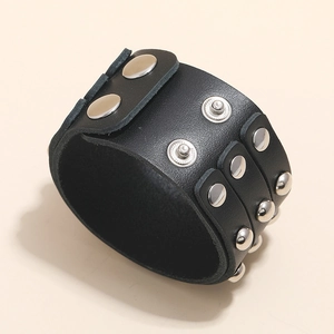 Macro shot of punk wide black leather bracelet featuring three rows of silver metal studs