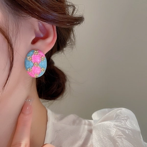 Close-up of vintage oval enamel floral earrings worn by a model in a French court style
