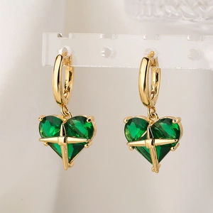 Gold-plated heart-shaped earrings with emerald green zircon on a minimalist stand