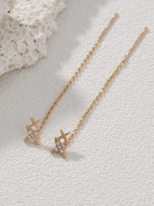 Detailed close-up of golden star-shaped dangle earrings with sparkling zircon inlay