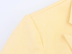 Macro shot of fine linen texture and precise shoulder stitching on light yellow blazer