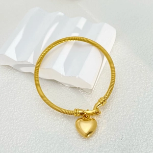 Golden twisted cable bracelet featuring a heart pendant on a white textured background