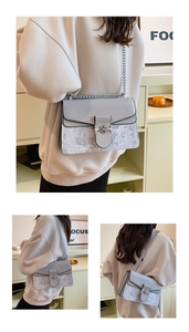 Detail view of a grey fashion chain bag featuring a floral pattern and silver flower buckle