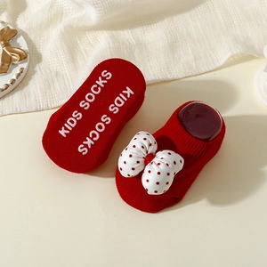 Close-up of red baby socks with bow detail and white anti-slip dots on the soles