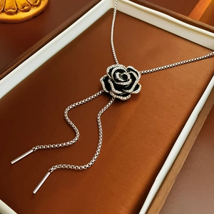 Macro detail of black enamel camellia necklace with silver chain in jewelry box